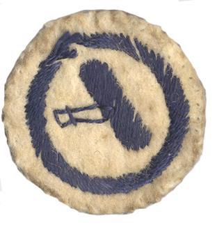 Image of round white felt badge featuring an aeroplane embroidered in dark blue thread, surrounded by a ring of dark blue stitching.