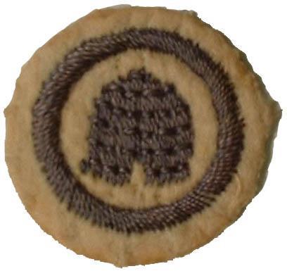 Photo of round white felt badge with logo of traditional bee skep embroidered in dark blue thread, surrounded by a ring of dark blue embroidery.