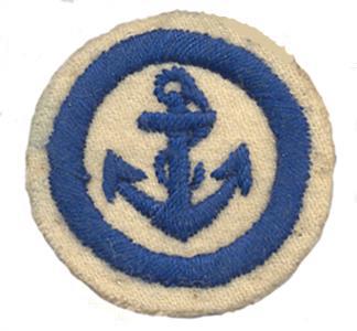 Photo of a white felt badge embroidered in dark blue felt showing a roped anchor within a stitched ring.