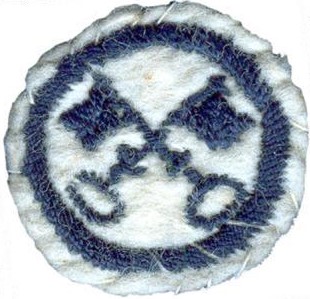 Image of round white felt badge with a logo of crossed keys embroidered in navy felt within an embroidered navy ring.