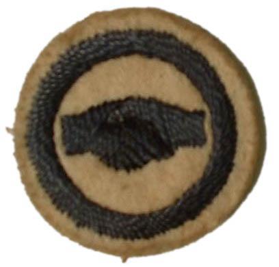 Image of round white felt badge with a logo of a handshake embroidered in navy thread, within a navy embroidered ring.