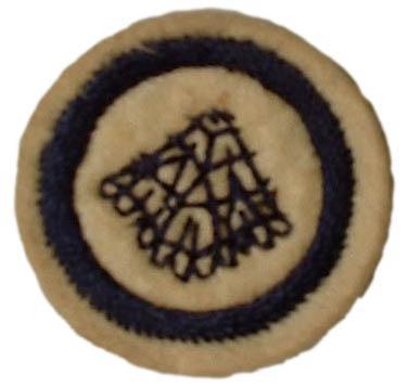 Image of round white felt badge with a logo of a section of lace embroidered in navy thread within an embroidered navy ring.