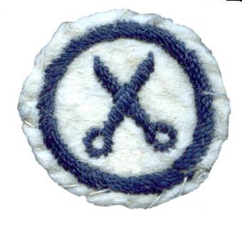 Image of round white felt badge with logo of open scissors embroidered in navy thread, within a navy embroidered ring.
