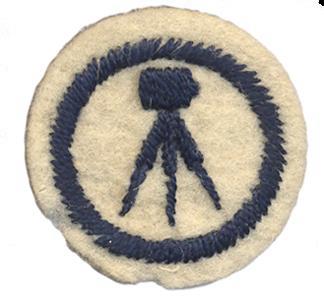 Image of round white felt badge with motif of plate camera on tripod embroidered in navy thread, within an embroidered navy ring.