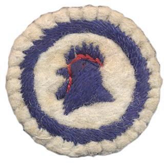 Image of round white felt badge with logo of cockerel's head facing left stitched in dark blue thread with red stitched highlights, within a blue embroidered ring
