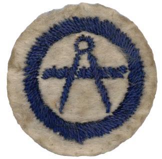 Photo of round white felt badge with logo of a pair of compasses and ruler stitched in dark blue thread, within an embroidered dark blue ring.